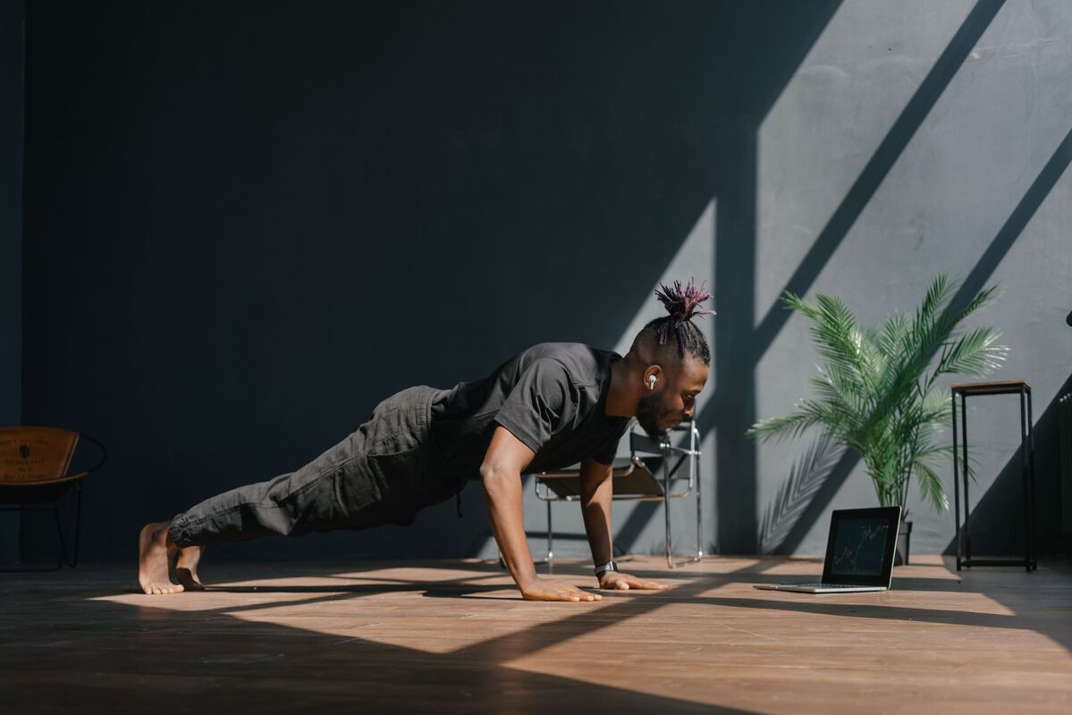 Une personne réalise un exercice de gainage accompagnée par son coach sportif
