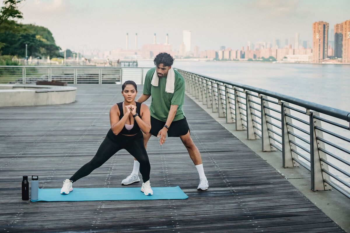 Un coach sportif accompagne une cliente pendant sa séance