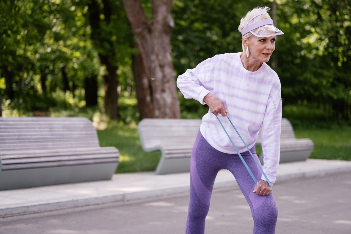 Une femme senior réalise un exercice de renforcement accompagnée par son coach sportif